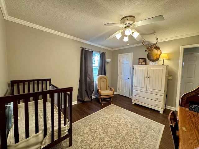 bedroom with ceiling fan, dark hardwood / wood-style flooring, a crib, and crown molding