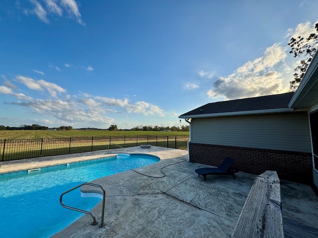 view of swimming pool with a patio area and a rural view