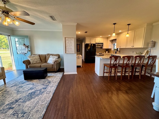 living room featuring a textured ceiling, ceiling fan, dark hardwood / wood-style floors, and ornamental molding