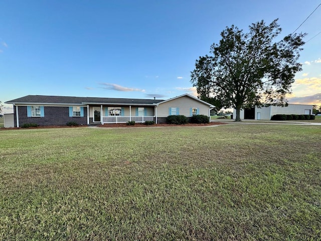 ranch-style home featuring covered porch and a front lawn