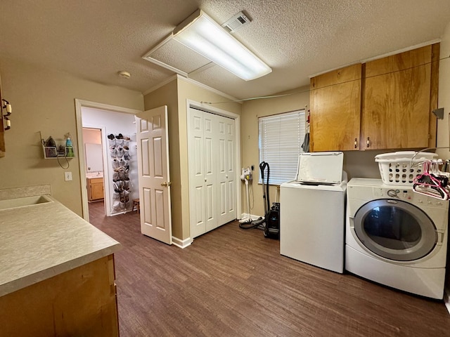 washroom with cabinets, dark hardwood / wood-style floors, separate washer and dryer, a textured ceiling, and ornamental molding