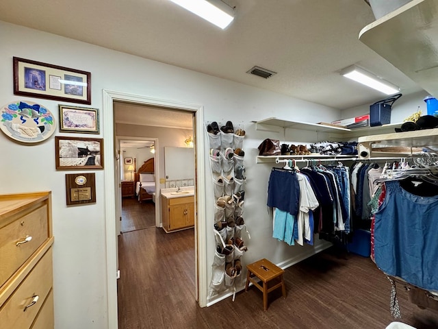 walk in closet with dark wood-type flooring