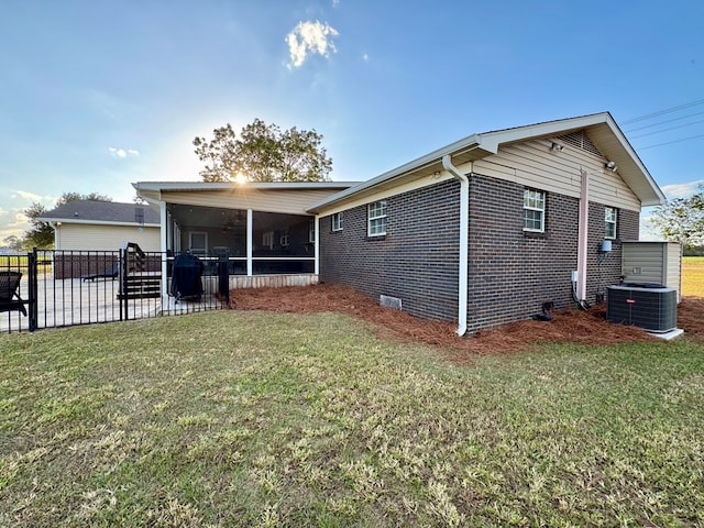 back of house featuring a sunroom, a yard, and central air condition unit