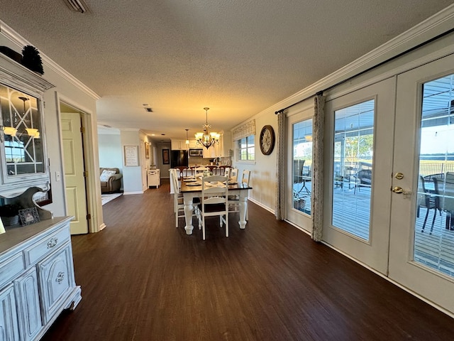 dining room with french doors, ornamental molding, a textured ceiling, dark wood-type flooring, and an inviting chandelier