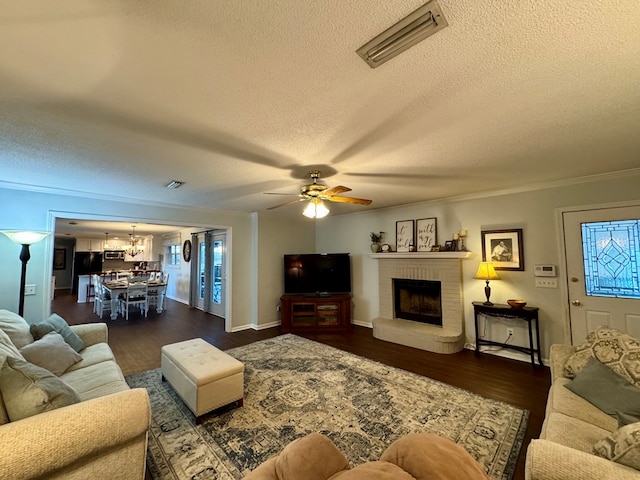 living room featuring a fireplace, dark hardwood / wood-style flooring, ornamental molding, and a textured ceiling