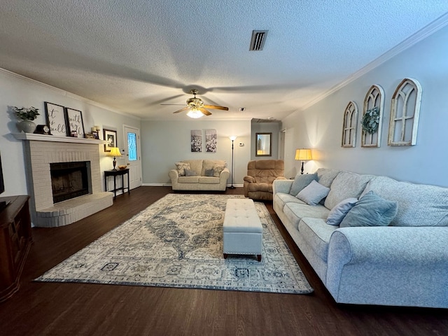 living room with ceiling fan, dark wood-type flooring, crown molding, a textured ceiling, and a fireplace