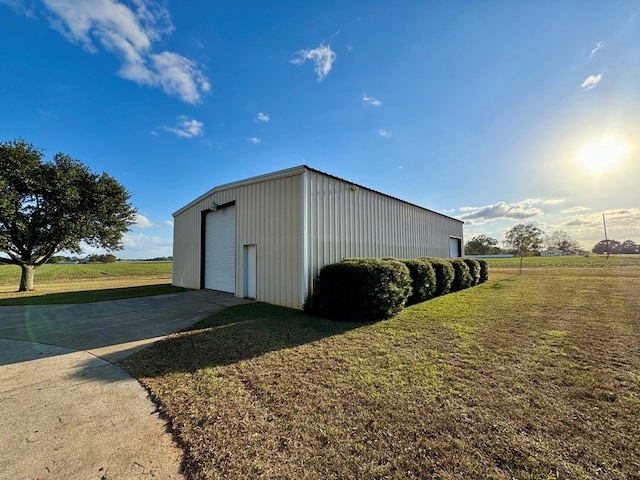 view of outdoor structure with a yard, a rural view, and a garage