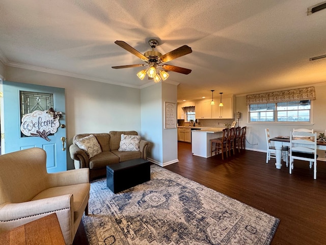 living room featuring ceiling fan, dark hardwood / wood-style flooring, a textured ceiling, and ornamental molding