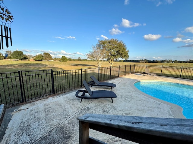 view of swimming pool with a lawn, a rural view, and a patio