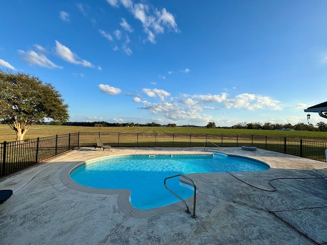 view of swimming pool with a patio area and a rural view