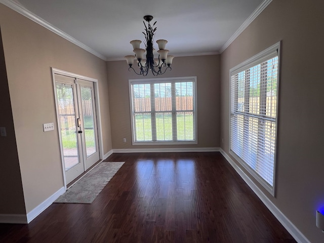 unfurnished dining area with crown molding, dark hardwood / wood-style flooring, french doors, and a notable chandelier