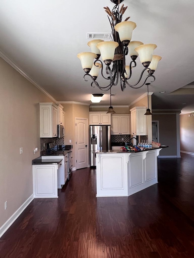 kitchen with white cabinets, appliances with stainless steel finishes, decorative backsplash, and a notable chandelier