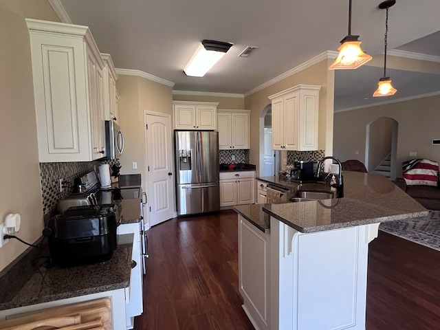 kitchen featuring kitchen peninsula, ornamental molding, stainless steel appliances, sink, and decorative light fixtures