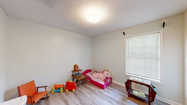 bedroom with baseboards, wood finished floors, and a textured ceiling