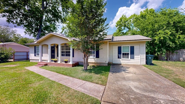 view of front of house featuring fence, covered porch, metal roof, and a front yard