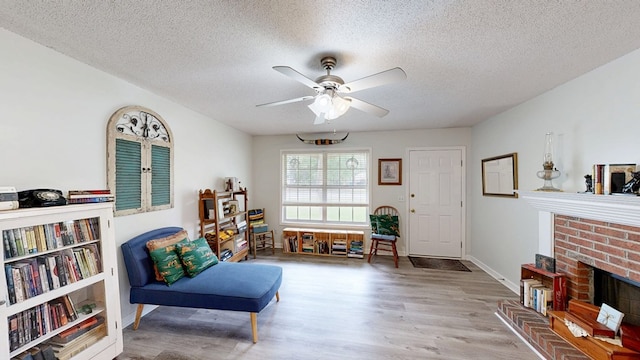 sitting room featuring wood finished floors, a ceiling fan, a textured ceiling, and a fireplace