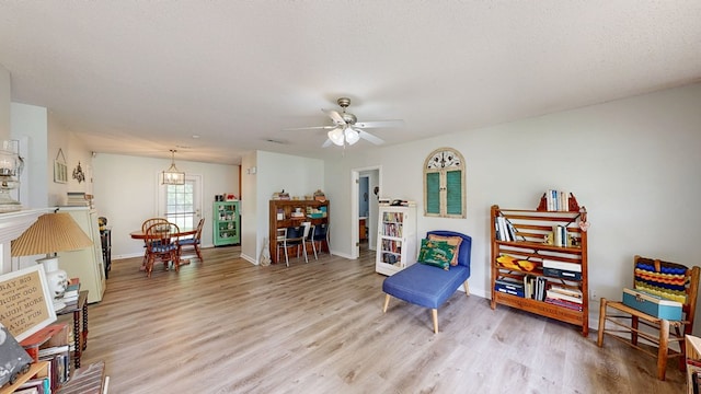 living area with baseboards, ceiling fan, and light wood finished floors