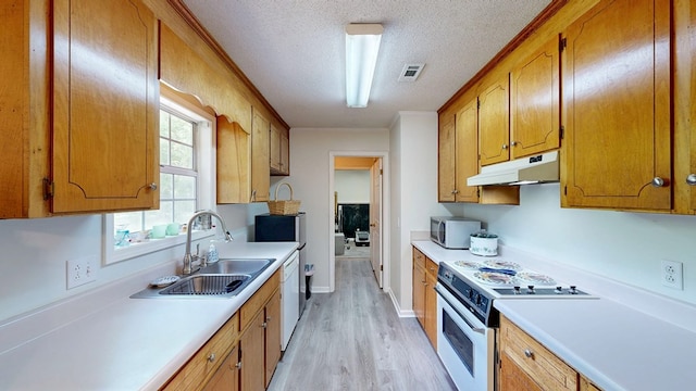 kitchen with white appliances, under cabinet range hood, light countertops, a sink, and a textured ceiling