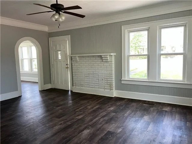 entrance foyer with crown molding, baseboards, arched walkways, dark wood-style floors, and a ceiling fan