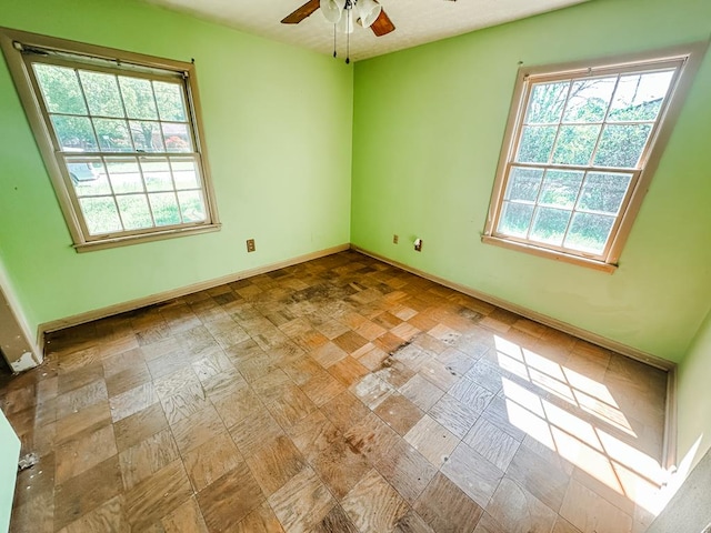 unfurnished room with baseboards and a ceiling fan