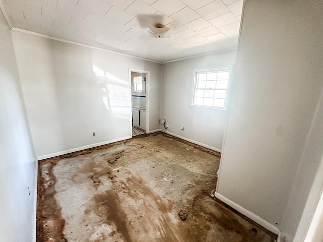 empty room with crown molding and baseboards