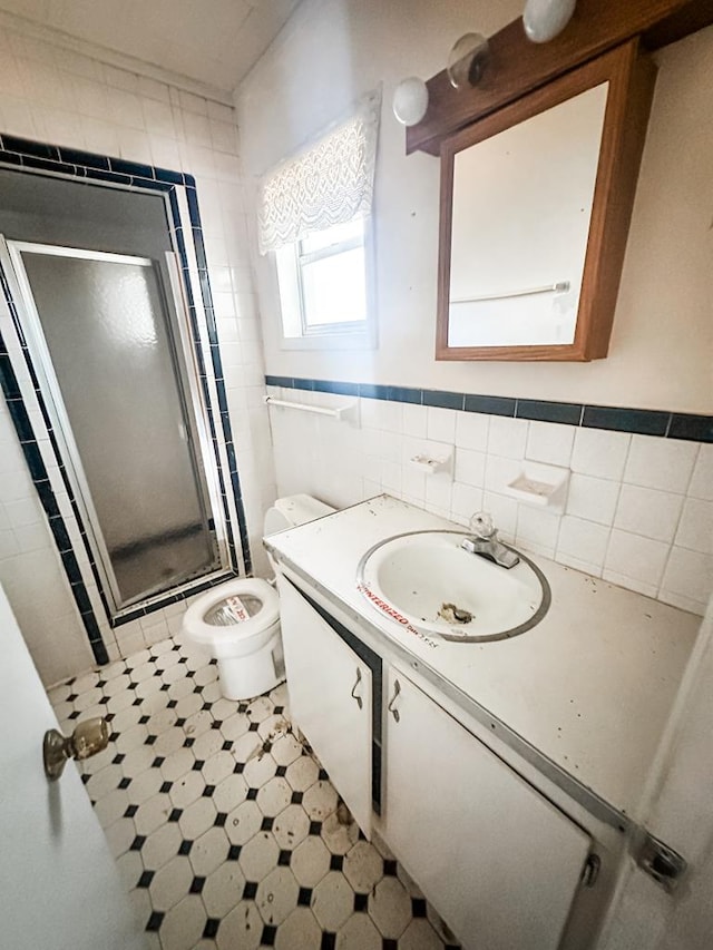 full bath with vanity, a stall shower, tile patterned floors, toilet, and tile walls