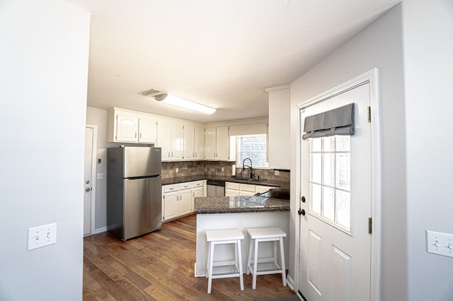 kitchen with white cabinets, stainless steel appliances, decorative backsplash, sink, and kitchen peninsula