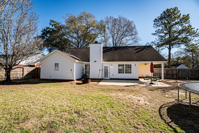 back of house with a lawn, a trampoline, and a patio area