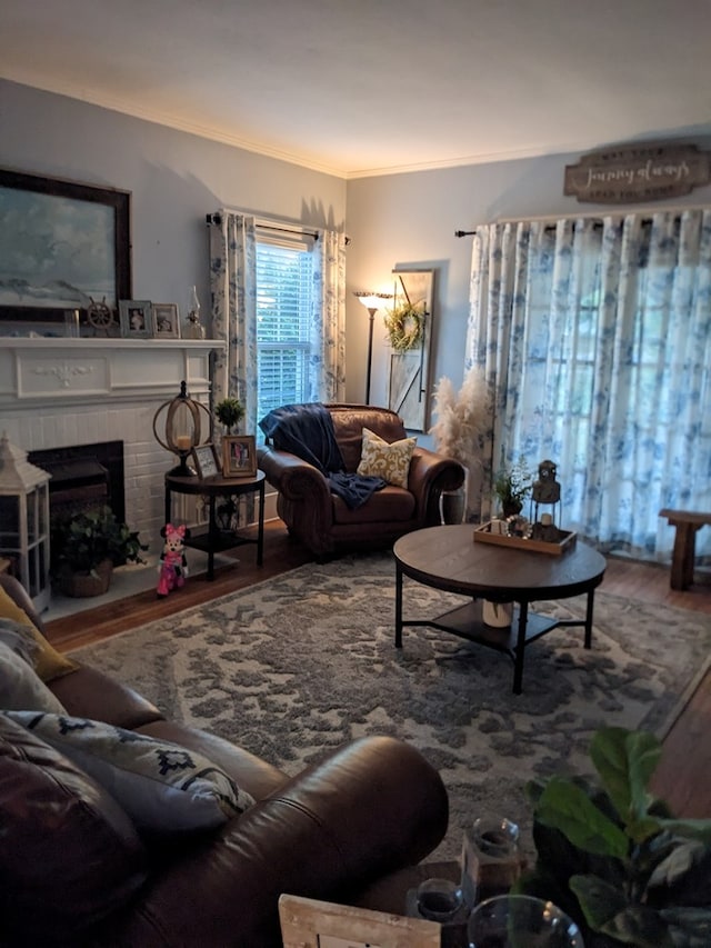 living room featuring crown molding, wood-type flooring, and a brick fireplace