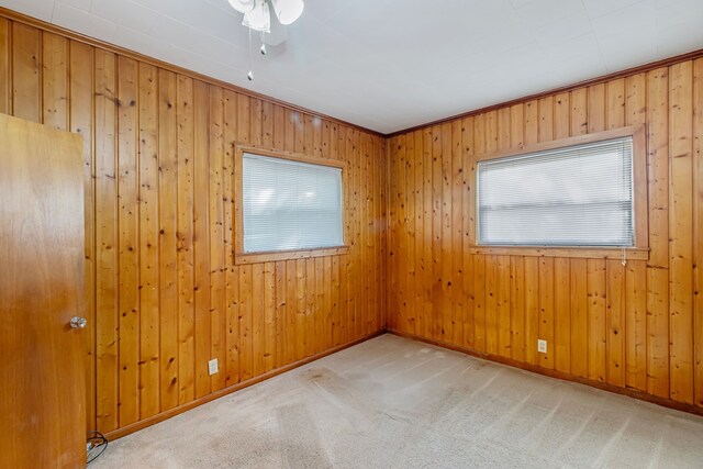 spare room with light colored carpet, ornamental molding, and wood walls