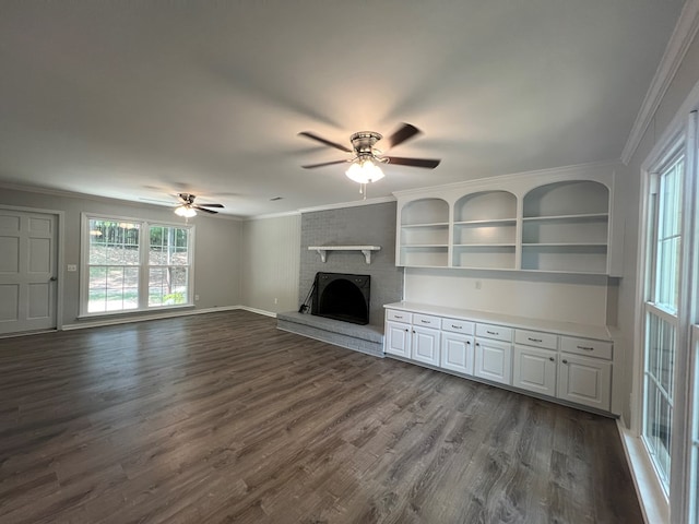 unfurnished living room with a brick fireplace, dark wood-type flooring, and crown molding