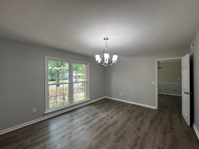 empty room featuring a notable chandelier and dark wood-type flooring