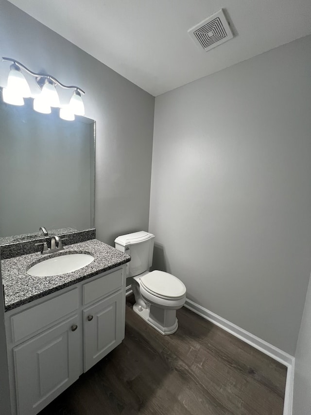 bathroom with hardwood / wood-style floors, vanity, and toilet