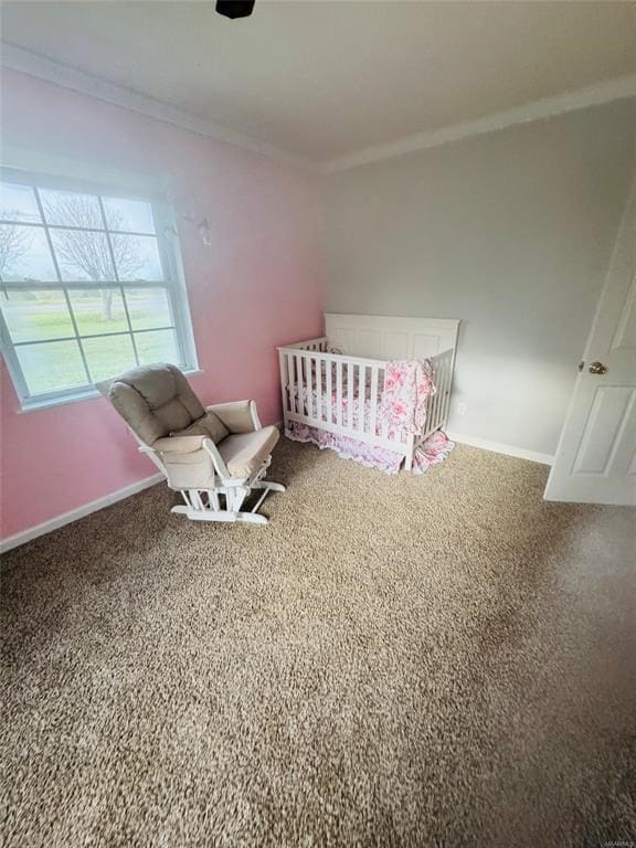 unfurnished bedroom featuring carpet floors, a nursery area, crown molding, and baseboards