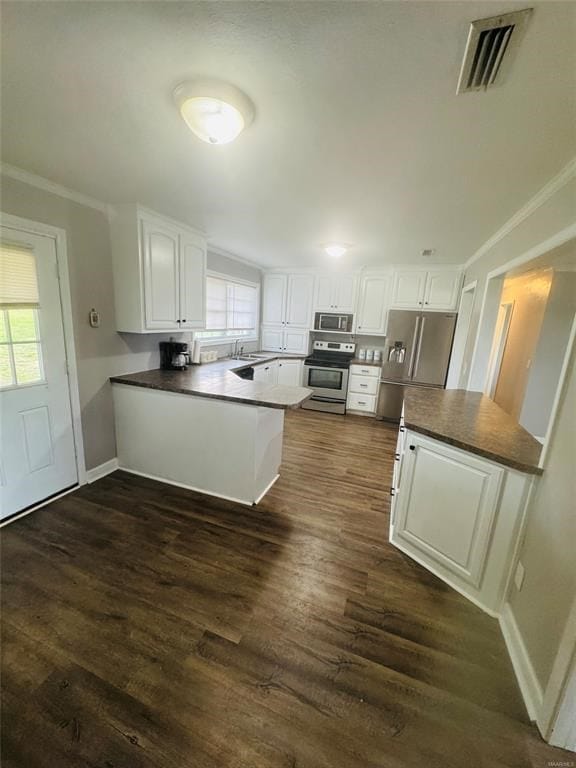 kitchen featuring visible vents, ornamental molding, appliances with stainless steel finishes, and a peninsula