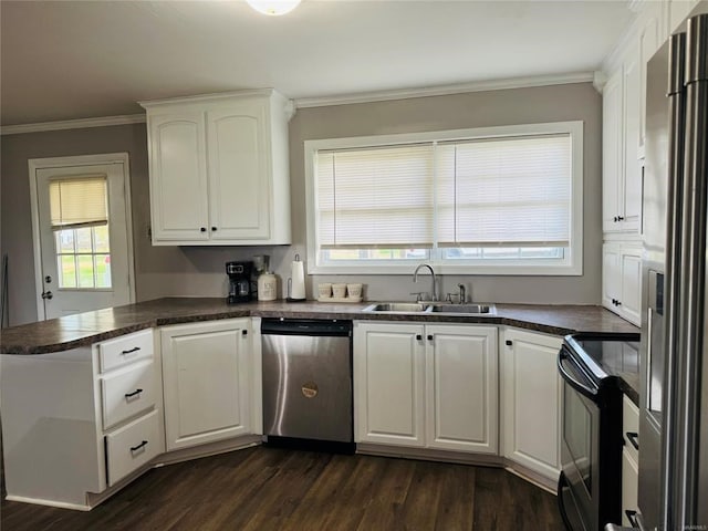 kitchen featuring a peninsula, dark countertops, appliances with stainless steel finishes, white cabinetry, and a sink