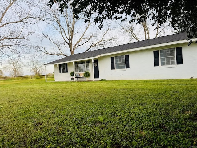 ranch-style home with a front yard and fence