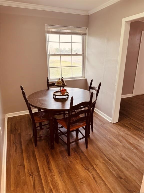 dining room featuring baseboards, wood finished floors, and crown molding