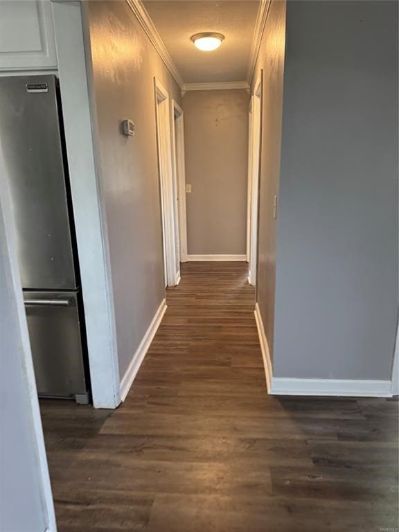 hallway with ornamental molding, dark wood-type flooring, and baseboards
