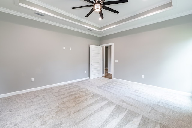 carpeted spare room with ceiling fan, a raised ceiling, and ornamental molding