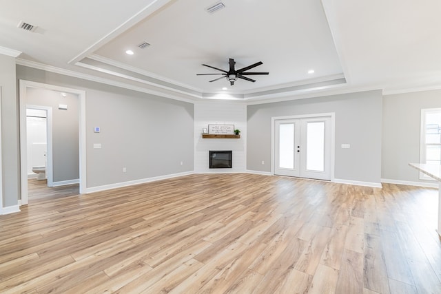 unfurnished living room featuring a raised ceiling and light hardwood / wood-style flooring