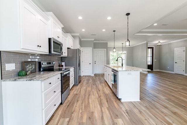 kitchen featuring decorative backsplash, light wood-type flooring, stainless steel appliances, a center island with sink, and white cabinets