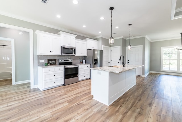 kitchen featuring sink, stainless steel appliances, decorative light fixtures, and light hardwood / wood-style floors