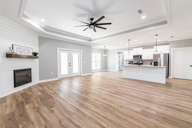 unfurnished living room with a fireplace, light hardwood / wood-style flooring, a raised ceiling, and crown molding