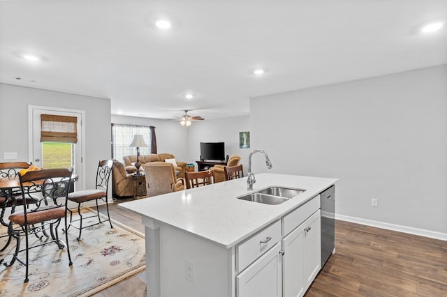 kitchen with white cabinetry, sink, dark wood-type flooring, stainless steel dishwasher, and a kitchen island with sink