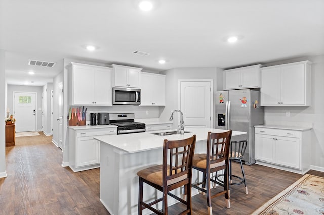 kitchen featuring a center island with sink, dark hardwood / wood-style flooring, white cabinets, and appliances with stainless steel finishes