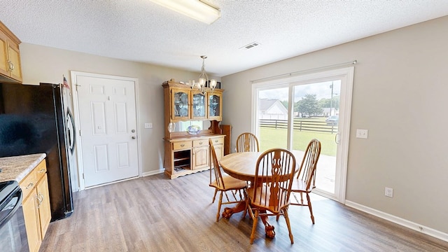 284 Alec Cir, Ozark, AL 36360 - dining space featuring light wood-style floors, a chandelier, a textured ceiling, and baseboards