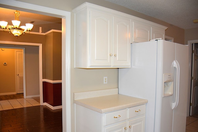 kitchen with light countertops, an inviting chandelier, white fridge with ice dispenser, white cabinets, and a textured ceiling