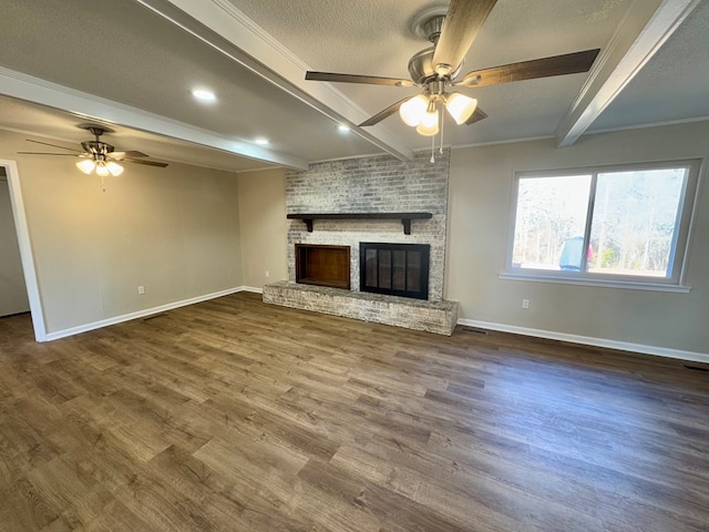 unfurnished living room featuring hardwood / wood-style flooring, a fireplace, beam ceiling, and a textured ceiling