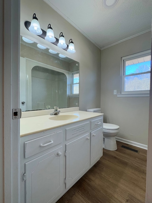 bathroom with wood-type flooring, a wealth of natural light, vanity, and toilet